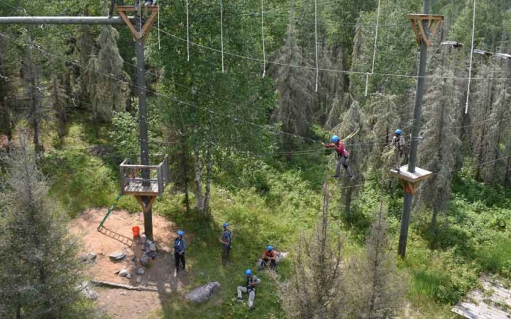 a group of adult students make their way through a ropes course on an outward bound trip